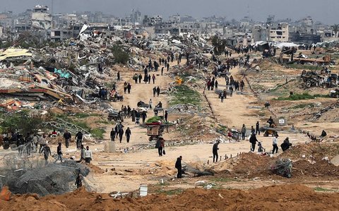 Warga Palestina berjalan melewati Koridor Netzarim, dekat Kota Gaza, Minggu (09/02/2025).