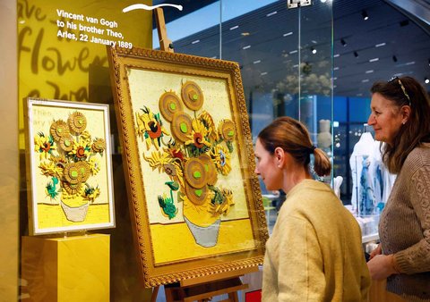 Pengunjung memperhatikan lukisan Bunga Matahari Van Gogh versi bata LEGO disamping versi asli lukisan yang dipajang di Museum Van Gogh Belanda di Amsterdam, Belanda, (28/02/2025) waktu setempat.