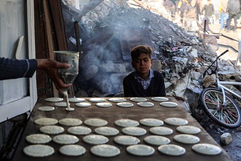 Seorang anak menyaksikan pembuatan kue tradisional "qatayef" di sebuah kios di pasar lama Zawiya pada hari pertama bulan puasa Ramadan  di Kota Gaza, Palestina, Sabtu (01/03/2025)