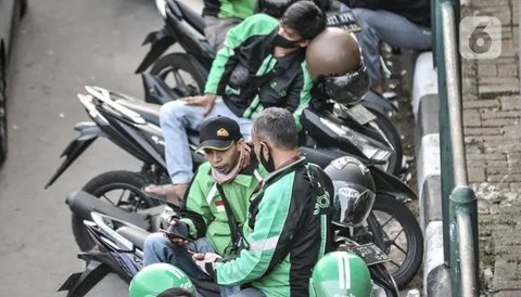 Pengemudi ojek online (ojol) memenuhi bahu jalan saat menunggu penumpang di kawasan Cililitan, Jakarta, Rabu (16/9/2020). Pemprov DKI Jakarta telah melarang ojol dan ojek pangkalan berkumpul