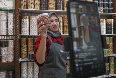 Pekerja menjual kue kering melalui fitur live streaming pada platform media sosial di industri rumahan Salzi Bakery, Depok, Jawa Barat, Jumat (14/3/2025).