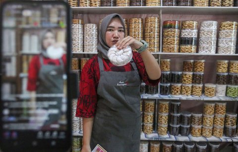 Pekerja menjual kue kering melalui fitur live streaming pada platform media sosial di industri rumahan Salzi Bakery, Depok, Jawa Barat, Jumat (14/3/2025).