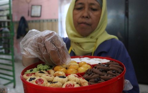 Pekerja menata kue kering pada toples di industri rumahan Salzi Bakery, Depok, Jawa Barat, Jumat (14/3/2025).