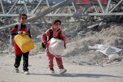 Anak-anak  membawa jerigen kosong saat mereka bergabung dengan orang-orang yang meninggalkan sektor timur Jalur Gaza di perbatasan dengan Israel,  Selasa (18/03/2025).