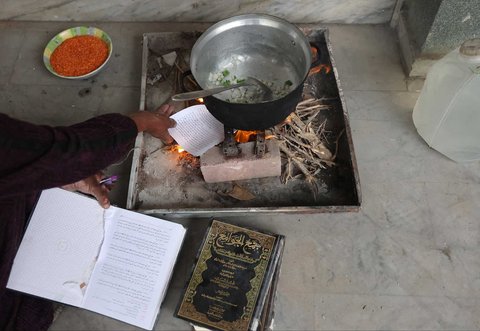Warga yang mengungsi membakar kertas buku yang dikumpulkan dari Universitas Islam yang hancur untuk memasak makanan di Kota Gaza Palestina, (21/03/2025) waktu setempat.