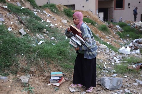 Warga yang mengungsi membakar kertas buku yang dikumpulkan dari Universitas Islam yang hancur untuk memasak makanan di Kota Gaza Palestina, (21/03/2025) waktu setempat.