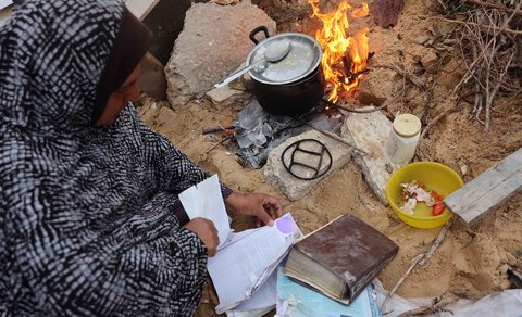Warga yang mengungsi membakar kertas buku yang dikumpulkan dari Universitas Islam yang hancur untuk memasak makanan di Kota Gaza Palestina, (21/03/2025) waktu setempat.