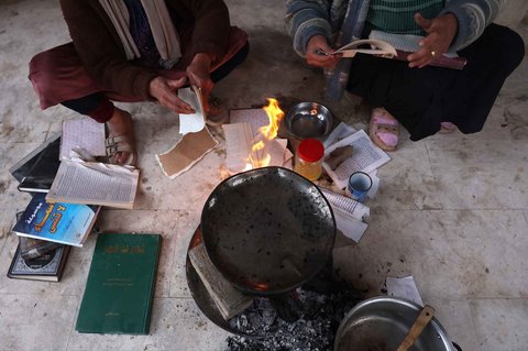 Warga yang mengungsi membakar kertas buku yang dikumpulkan dari Universitas Islam yang hancur untuk memasak makanan di Kota Gaza Palestina, (21/03/2025) waktu setempat.
