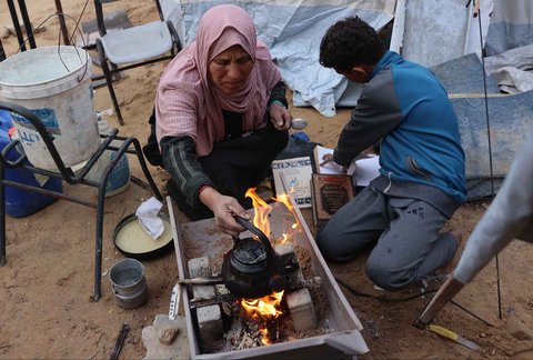 Warga yang mengungsi membakar kertas buku yang dikumpulkan dari Universitas Islam yang hancur untuk memasak makanan di Kota Gaza Palestina, (21/03/2025) waktu setempat.