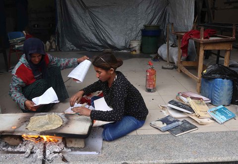 Warga yang mengungsi membakar kertas buku yang dikumpulkan dari Universitas Islam yang hancur untuk memasak makanan di Kota Gaza Palestina, (21/03/2025) waktu setempat.