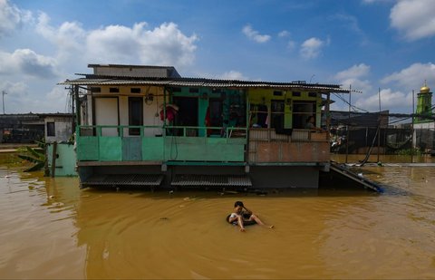 Warga beraktivitas saat banjir merendam permukiman di sekitar Sungai Ciliwung, Jakarta, Senin (3/3/2025). Banjir akibat luapan Sungai Ciliwung merendam sejumlah wilayah di Jakarta dengan ketinggian mencapai 2 meter.