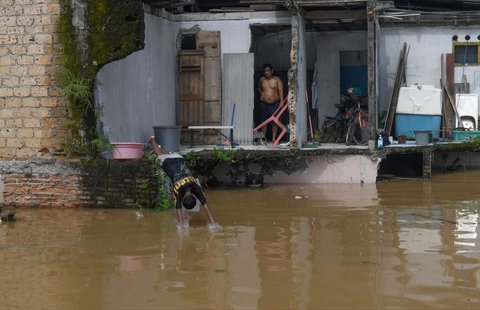 Seorang anak bermain air saat banjir merendam permukiman di sekitar Sungai Ciliwung, Jakarta, Senin (3/3/2025). Banjir akibat luapan Sungai Ciliwung merendam sejumlah wilayah di Jakarta dengan ketinggian mencapai 2 meter.