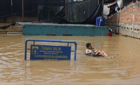 Seorang anak bermain air saat banjir merendam permukiman di sekitar Sungai Ciliwung, Jakarta, Senin (3/3/2025). Banjir akibat luapan Sungai Ciliwung merendam sejumlah wilayah di Jakarta dengan ketinggian mencapai 2 meter.