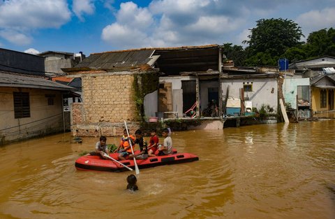 Anak-anak menaiki perahu karet saat banjir merendam permukiman di sekitar Sungai Ciliwung, Jakarta, Senin (3/3/2025). Banjir akibat luapan Sungai Ciliwung merendam sejumlah wilayah di Jakarta dengan ketinggian mencapai 2 meter.