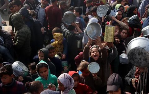 Warga, termasuk anak-anak pengungsi Palestina berkumpul untuk menerima bantuan makanan yang didistribusikan di Deir al-Balah, Jalur Gaza tengah pada 16 Januari 2025. (Eyad BABA/AFP)