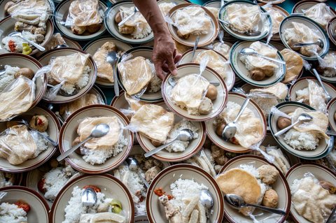 Umat Muslim menerima makanan gratis untuk berbuka puasa selama Ramadan di Masjid Jogokariyan di Yogyakarta, pada 2 Maret 2025.