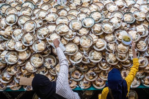 Umat Muslim menerima makanan gratis untuk berbuka puasa selama Ramadan di Masjid Jogokariyan di Yogyakarta, pada 2 Maret 2025.