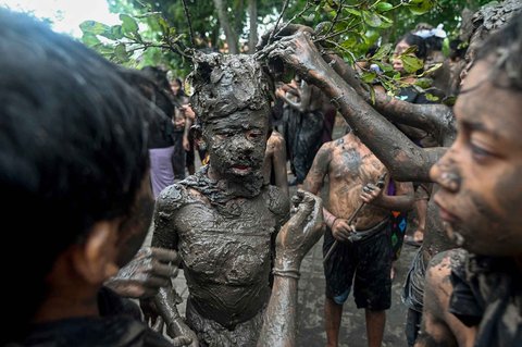Anak-anak menutupi diri mereka dengan lumpur saat kegiatan tradisi mandi lumpur di Desa Kedonganan, Badung, Bali, Minggu (30/03/2025).