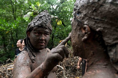 Anak-anak menutupi diri mereka dengan lumpur saat kegiatan tradisi mandi lumpur di Desa Kedonganan, Badung, Bali, Minggu (30/03/2025).