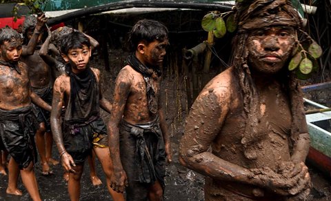 Anak-anak menutupi diri mereka dengan lumpur saat kegiatan tradisi mandi lumpur di Desa Kedonganan, Badung, Bali, Minggu (30/03/2025).
