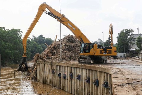Petugas menggunakan alat berat saat memindahkan tumpukan sampah, yang telah diangkut dari Sungai Ciliwung, ke atas truk di Saringan Sampah TB Simatupang (SSTBS), Jakarta, Rabu (5/3/2025).