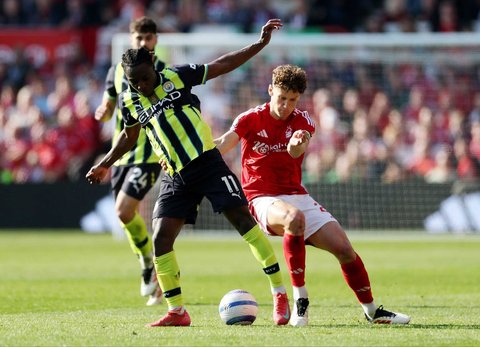 Pemain Manchester City Jeremy Doku (kiri) berebut bola dengan pemain  Nottingham Forest Ryan Yates di City Ground, Inggris, Sabtu (8/3/2025) malam WIB.