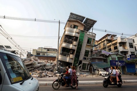 Sejumlah warga melintas di depan bangunan tempat tinggal yang runtuh akibat gempa bumi dahsyat di Mandalay, Myanmar, pada 31 Maret 2025.