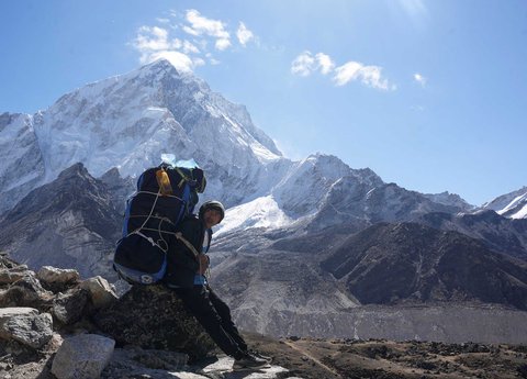 Porter beristirahat  dengan latar belakang Gunung Everest dari Lobuche di distrik Solukhumbu, Nepal (12/04/2025)