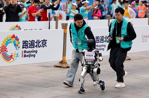 Para teknisi berlari bersama robot humanoid