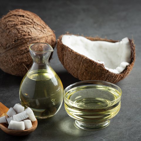 Semangkuk minyak kelapa beserta buah kelapa tua yang utuh (Foto Dok: Freepik/jcomp).