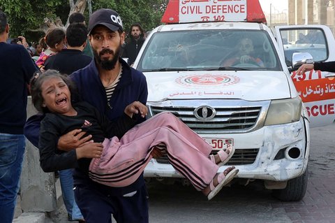 Pria Palestina menggendong seorang anak yang terluka setelah sebuah sekolah hancur akibat serangan Israel di lingkungan al-Tuffah, Jalur Gaza, Palestina, pada Jumat (4/4/2025).