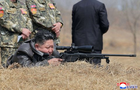 Wajahnya tampak serius. Mata kanan mengintai tajam melalui teropong, sementara telunjuknya siaga di pelatuk. Begitulah aksi Kim Jong-un saat menjajal senapan runduk terbaru buatan dalam negeri.