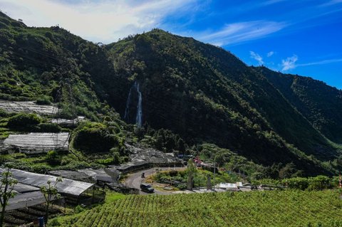 Sejumlah pengendara melintasi kawasan pegunungan yang dijuluki 'Swiss van Java' dengan latar belakang Air Terjun Sikarim di kawasan Desa Wisata Sembungan, Wonosobo, Jawa Tengah, Senin (7/4/2025).