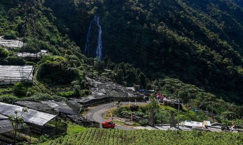 Sejumlah pengendara melintasi kawasan pegunungan yang dijuluki 'Swiss van Java' dengan latar belakang Air Terjun Sikarim di Desa Wisata Sembungan, Wonosobo, Jawa Tengah, Senin (7/4/2025).