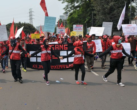 Massa buruh berjalan menuju Istana Negara saat aksi Hari Buruh di Jakarta, Senin (1/5). Dalam aksinya para buruh meminta sistem kerja kontrak dan upah rendah dihapus. (Liputan6.com/Helmi Afandi)