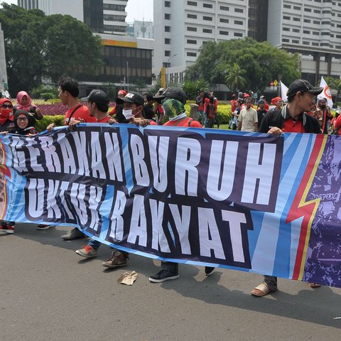 Massa aksi Hari Buruh membawa spanduk saat memperingati Hari Buruh Internasional di Jakarta, Senin (1/5). Dalam aksinya para buruh meminta sistem kerja kontrak dan upah rendah dihapus. (Liputan6.com/Helmi Afandi)