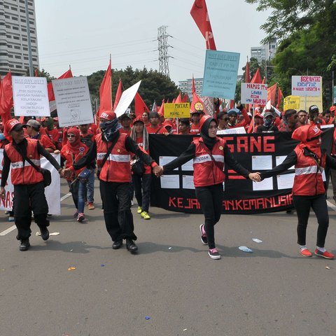 Massa buruh berjalan menuju Istana Negara saat aksi Hari Buruh di Jakarta, Senin (1/5). Dalam aksinya para buruh meminta sistem kerja kontrak dan upah rendah dihapus. (Liputan6.com/Helmi Afandi)