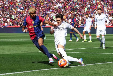 Pemain Barcelona Lamine Yamal berebut bola dengan pemain Real Madrid Fran Garcia pada La Liga 2024/2025 di  Estadi Olimpic Lluis Companys, Barcelona, Spanyol, Minggu (11/05/2025).