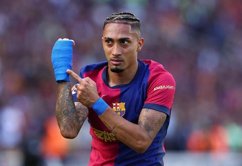 Pemain Barcelona Raphinha menunjuk tangannya yang diperban mencetak gol keempat ke gawang Real Madrid  pada La Liga 2024/2025 di  Estadi Olimpic Lluis Companys, Barcelona, Spanyol, Minggu (11/05/2025).