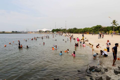 Sejumlah pengunjung menghabiskan libur panjang perayaan Waisak di Pantai Lagoon, Taman Impian Jaya Ancol, Jakarta, Selasa (13/5/2025).