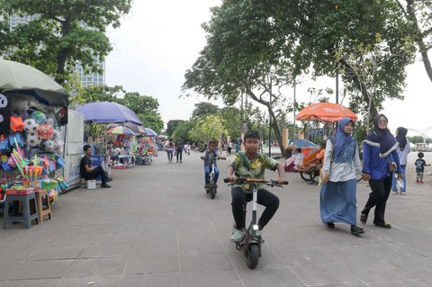 Anak-anak bersepeda saat menghabiskan libur panjang perayaan Waisak di Pantai Lagoon, Taman Impian Jaya Ancol, Jakarta, Selasa (13/5/2025).