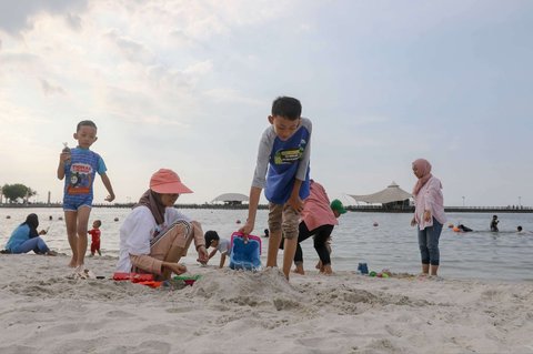 Anak-anak bermain pasir saat menghabiskan libur panjang perayaan Waisak di Pantai Lagoon, Taman Impian Jaya Ancol, Jakarta, Selasa (13/5/2025).