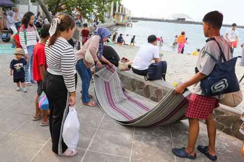 Sejumlah pengunjung menghabiskan libur panjang perayaan Waisak di Pantai Lagoon, Taman Impian Jaya Ancol, Jakarta, Selasa (13/5/2025).