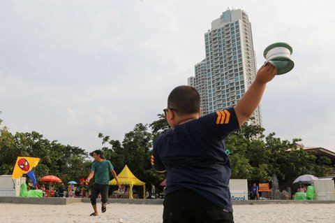 Sejumlah pengunjung menghabiskan libur panjang perayaan Waisak di Pantai Lagoon, Taman Impian Jaya Ancol, Jakarta, Selasa (13/5/2025).