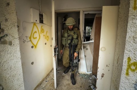 Tentara Israel berjalan di sebuah rumah yang rusak di Kfar Aza, salah satu kibbutzim yang diserang Hamas.