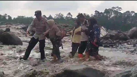 Anggota Polsek Candipuro membantu pelajar menyeberangi sungai aliran lahar di Desa Jugosari untuk pergi ke sekolah