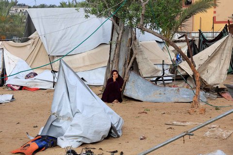 Warga  duduk di lokasi serangan Israel terhadap kamp tenda yang menampung orang-orang terlantar, di Khan Younis, Jalur Gaza selatan, Minggu (18/05/2025).