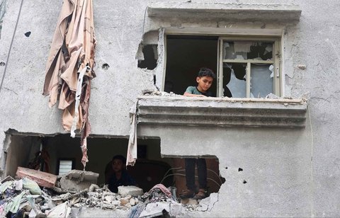 Seorang anak melihat ke luar rumah yang rusak di lokasi serangan Israel, di Jalur Gaza bagian tengah, Minggu (18/05/2025).