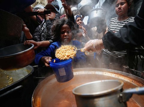 Warga Palestina antri mengambil  makanan yang dimasak di  Dapur Amal, di Beit Lahiya, Jalur Gaza utara, Senin (28/04/2025).