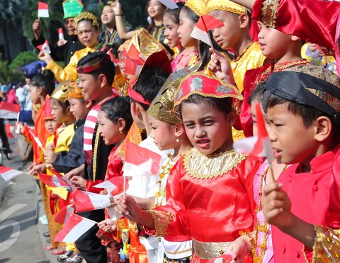 Antusias murid sekolah minggu Gereja Eban Haezer mengenakan baju adat sambil melambaikan bendera nasional di Bundaran HI Jakarta, Minggu (21/8). Menyanyikan lagu Indonesia Raya dan lagu daerah, mereka memperingati HUT RI ke 71. (Liputan6.com/Angga Yuniar)